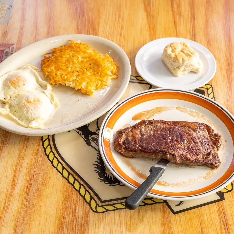Steak and eggs with hash browns and a biscuit.