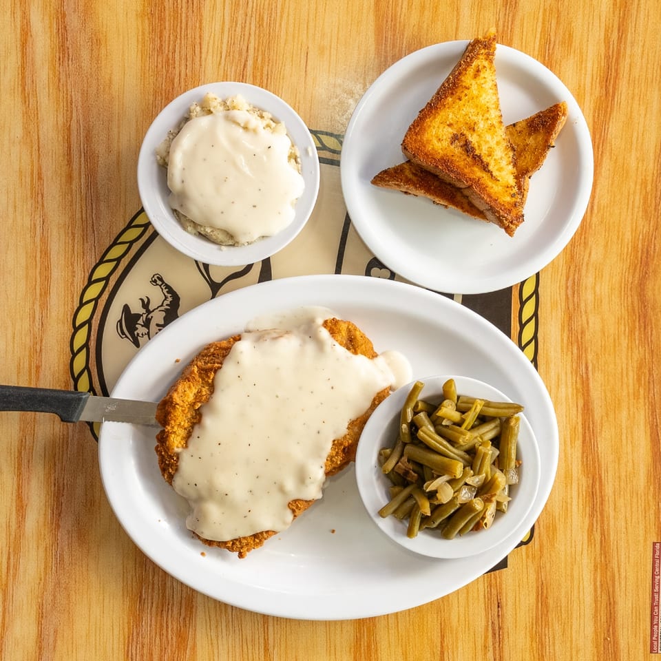 Country fried chicken with cream gravy and vegetables.