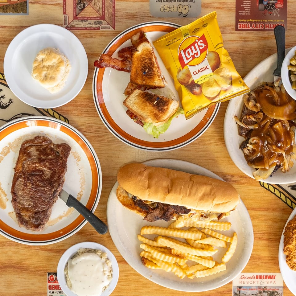 Rodeo Diner table spread with steak, sandwiches, and comfort food.