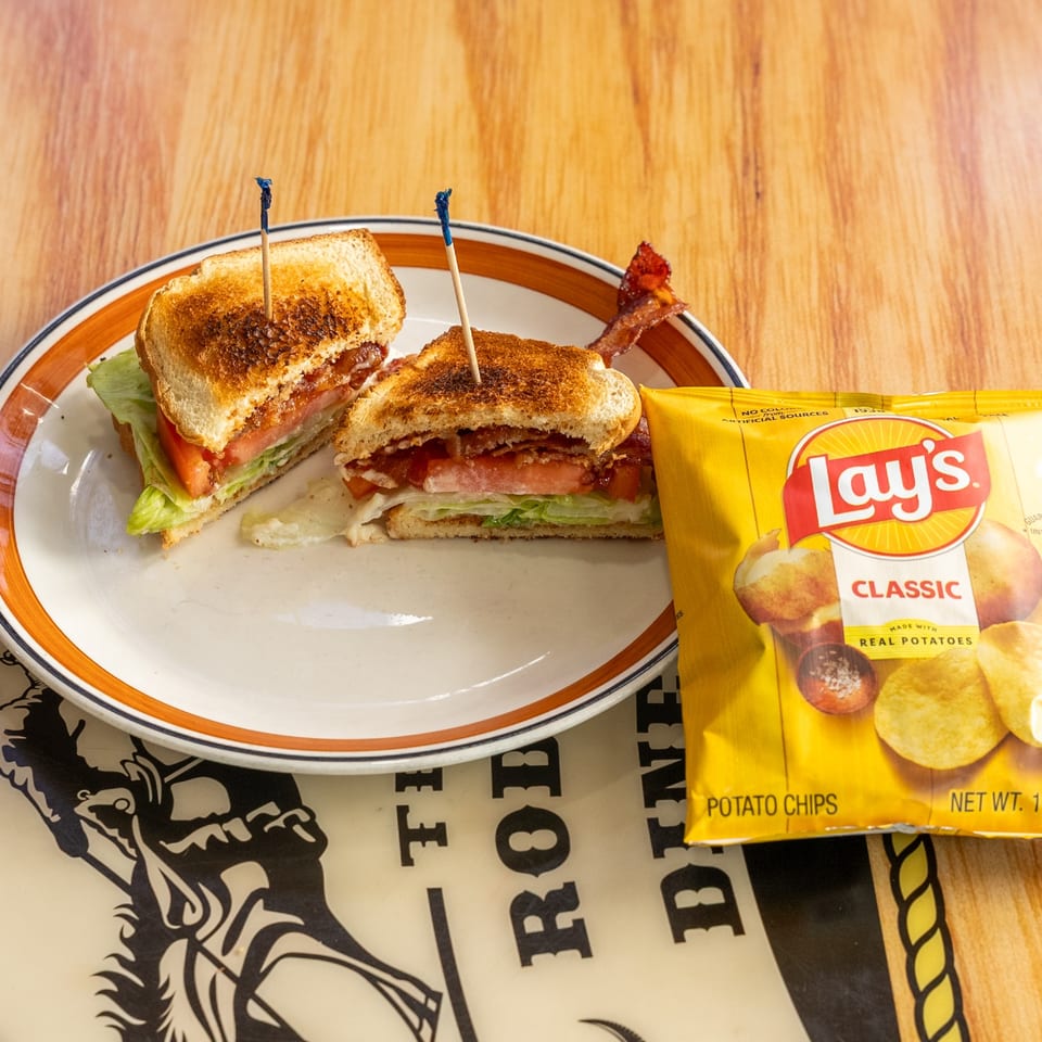 Bacon, lettuce, and tomato sandwich with potato chips.